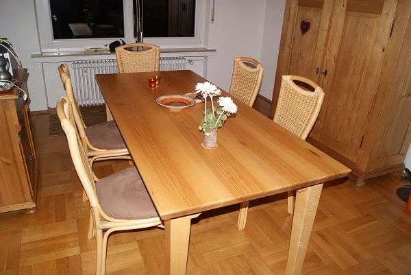 Holztisch mit vier Stühlen in einem Esszimmer mit Parkettboden und Dekoration.